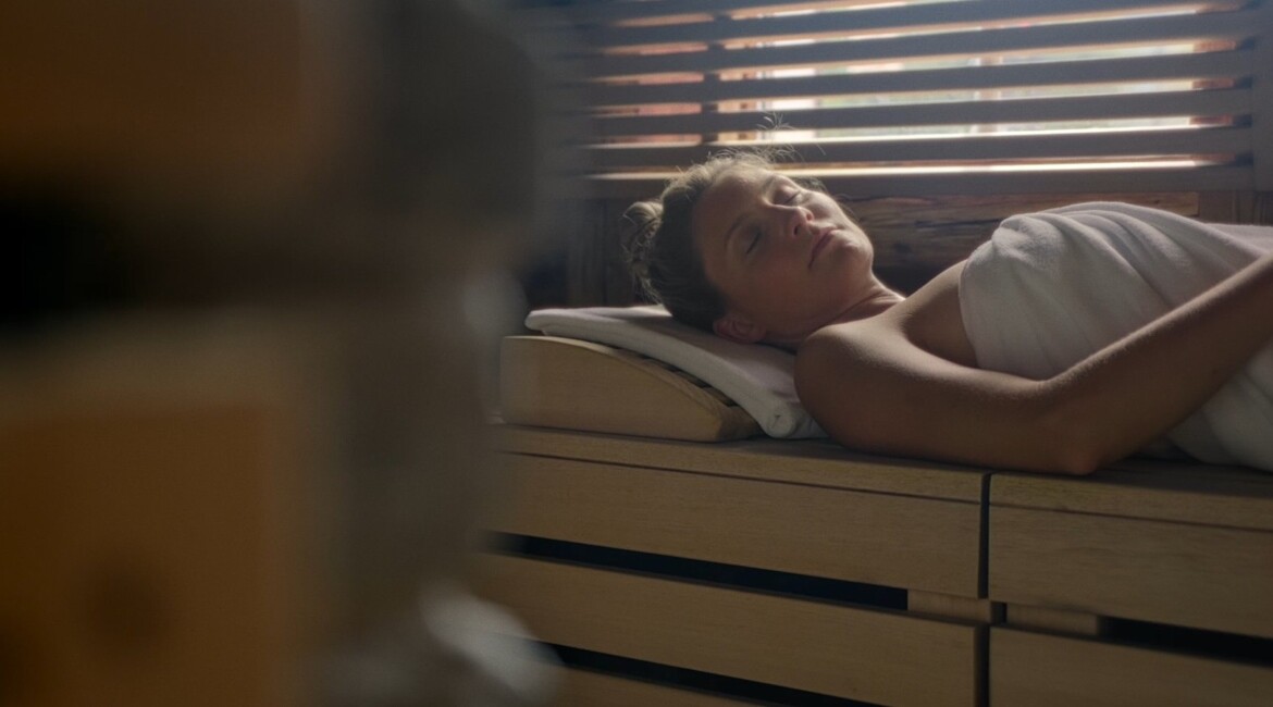 A person relaxing in a sauna wrapped in a towel, enjoying a peaceful moment.