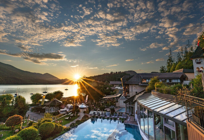 Sonnenuntergang über dem Fuschlsee im Sommer mit Blick auf den Wellnessbereich des Hotel Ebner's Waldhof am See.
