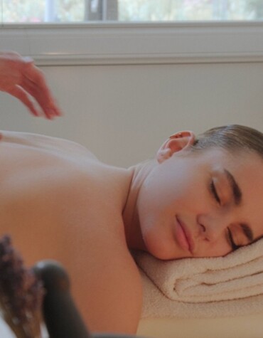 Eine Person genießt eine entspannende Massage in einem Wellnessbereich mit Kerzenlicht.