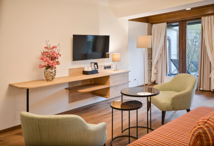 Modernes Doppelzimmer mit Sitzgelegenheit und Balkon im Hotel Ebner's Waldhof am See.