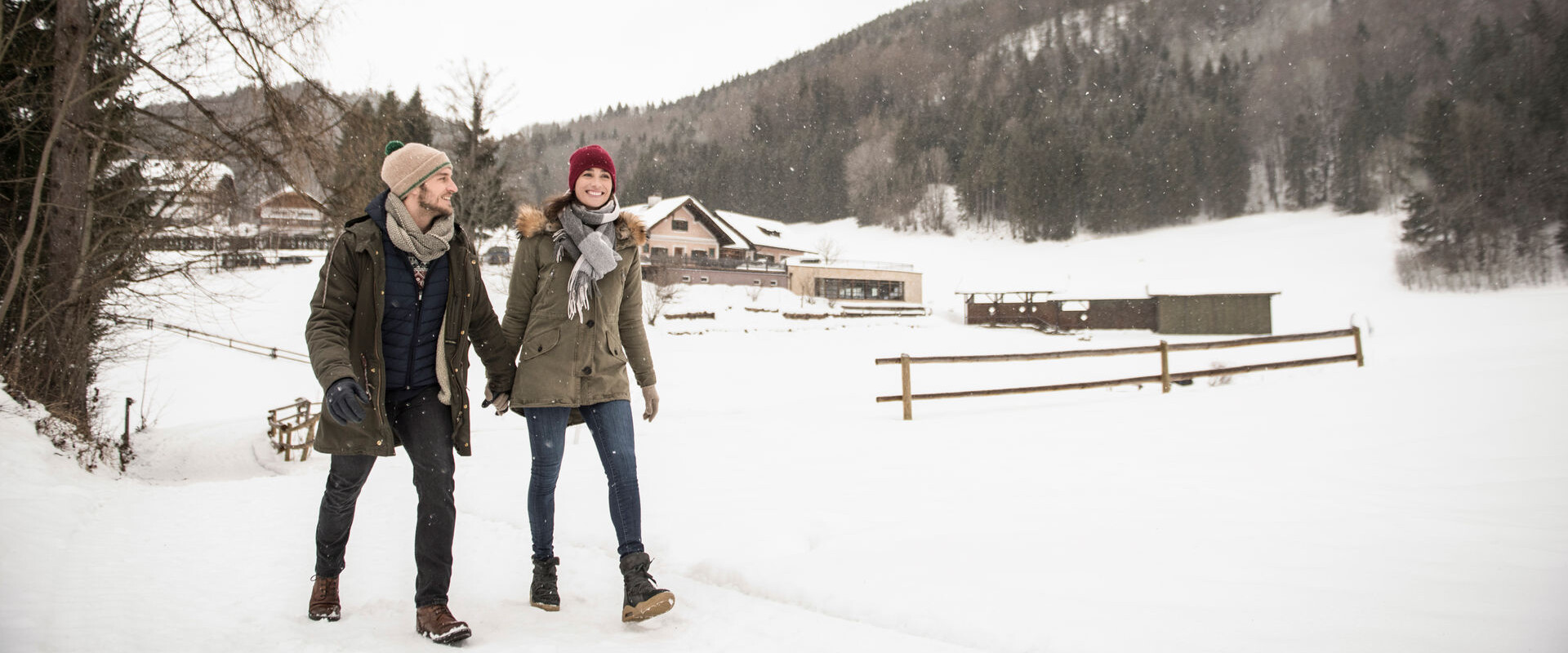 Pärchen beim Winterwandern durch den tief verschneiten Wald am Fuschlsee, Salzburg.