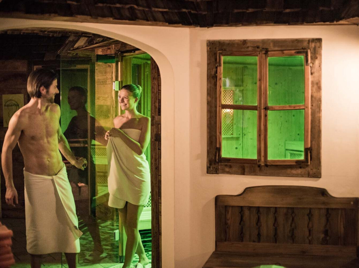 Ein Paar verlässt eine Sauna in einem gemütlichen Wellnessbereich des Hotels Waldhof am Fuschlsee.