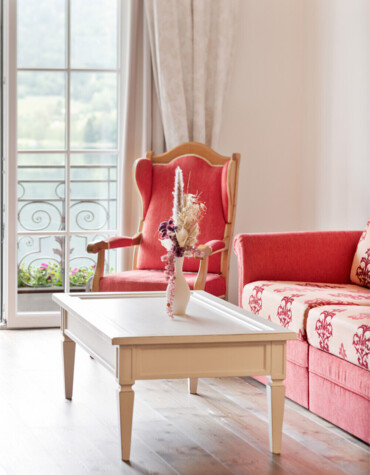 Elegant living room with red chairs and sofa, white coffee table, and window view.