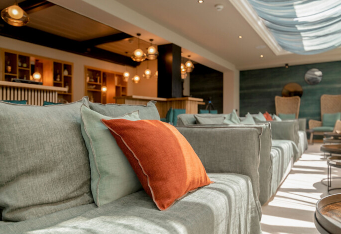 Gemütlicher Lounge-Bereich in der Seebar im Waldhof mit bequemen Sofas, dekoriert mit bunten Kissen und stilvollen Leuchten.