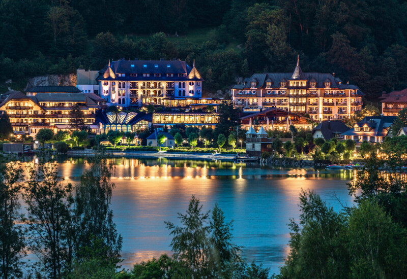 Waldhof Fuschlsee Resort am Fuschlsee bei Nacht, umgeben von beleuchteten Gebäuden und ruhiger Natur.