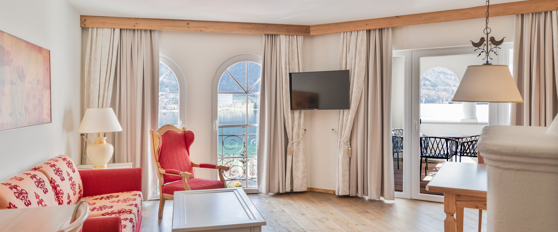 Bright living room with elegant furniture, arched windows, and a view of the lake.