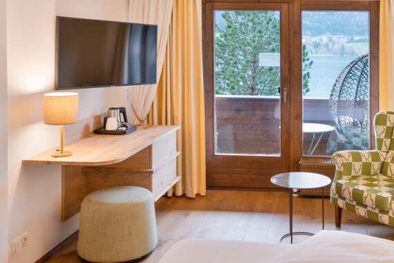 Cozy hotel room with a view of the lake, featuring a TV, lamp, and seating area.