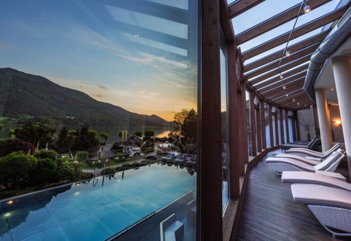 Blick aus dem Ruheraum auf den Pool bei Sonnenuntergang.
