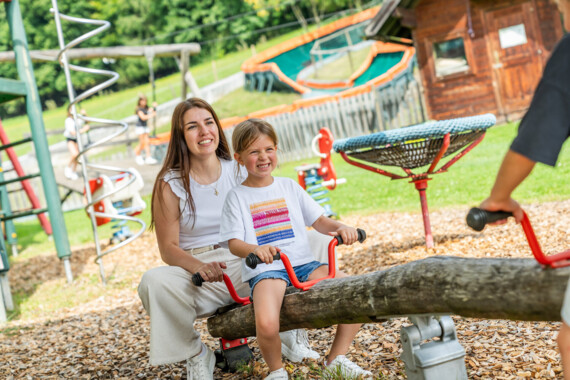 Zwei Kinder beim spielen auf dem Outdoor-Spielplatz im Familienhotel Waldhof Fuschlsee Resort.