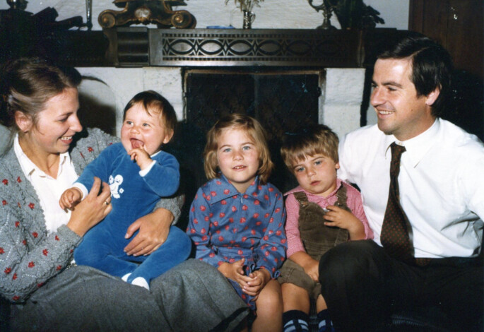 A family sits together by a fireplace, smiling and enjoying each other's company.