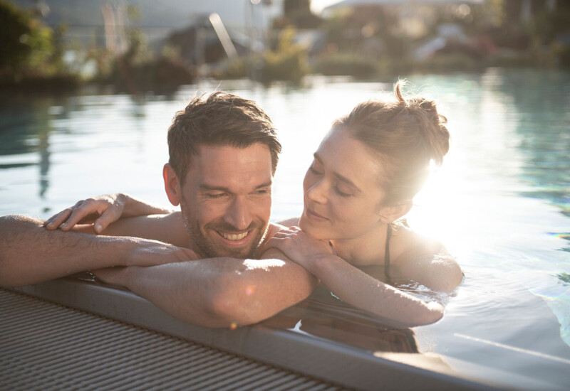 Couple relaxing in a pool at Waldhof Fuschlsee Resort, enjoying the serene atmosphere.