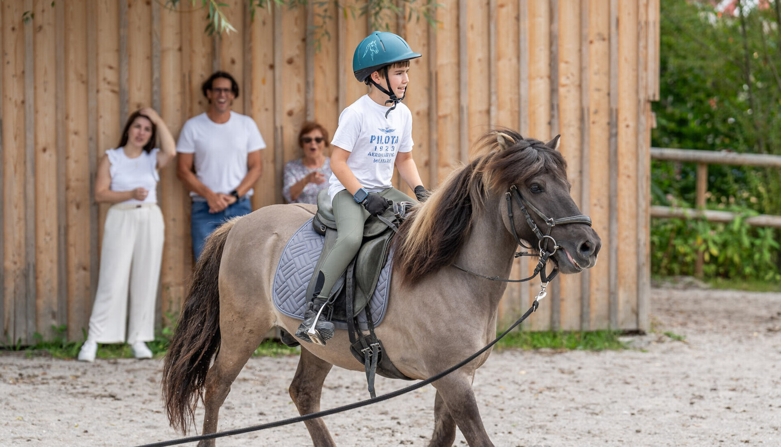 Großeltern sitzen mit der Enkelin am Strand des Fuschlsees und lassen Seifenblasen steigen.