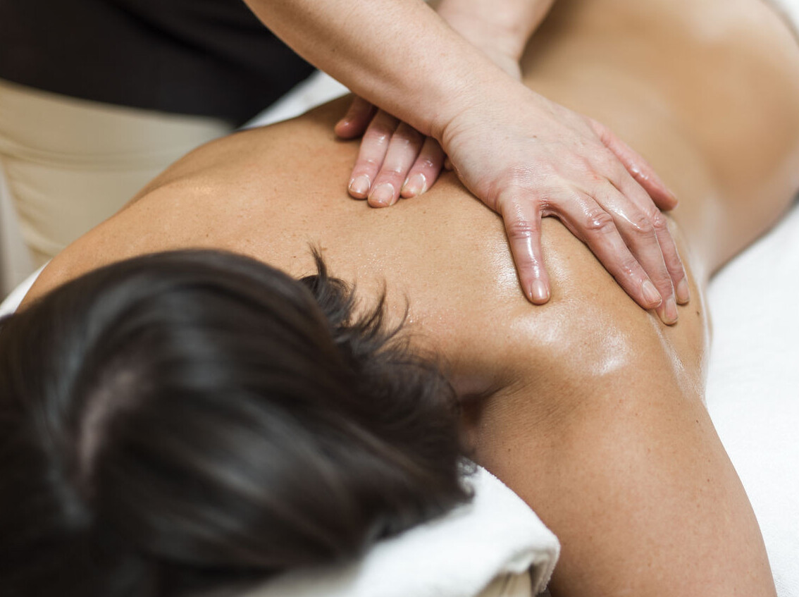 A person receiving a relaxing back massage on a massage table, covered with a white towel.