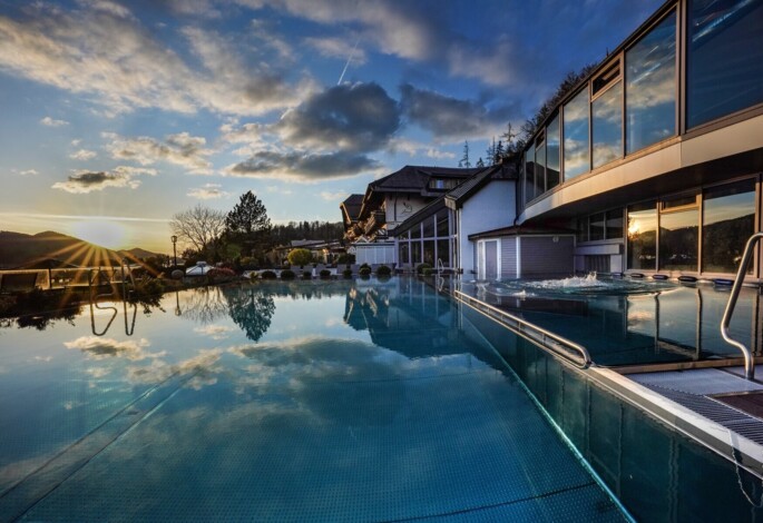 Außenpool des 4*S Wellnesshotel Waldhof Fuschlsee Resort bei Sonnenuntergang.