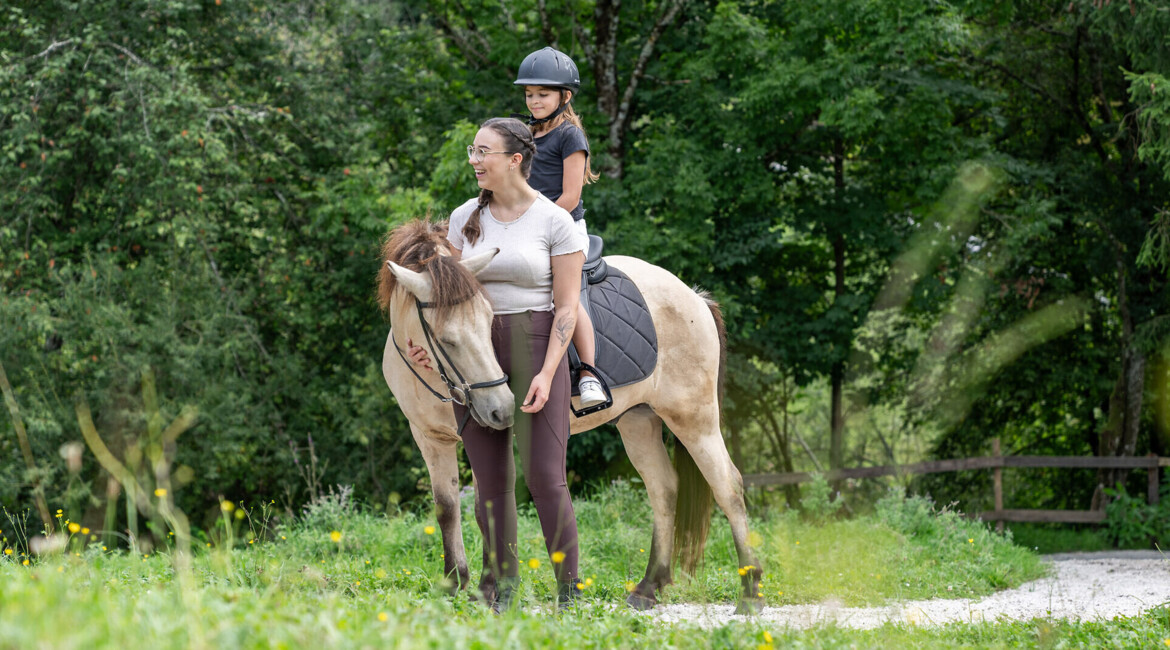 Kind auf einem Tretauto im Outodoor-Spielebereich des Familienhotels Waldhof Fuschlsee Resorts.