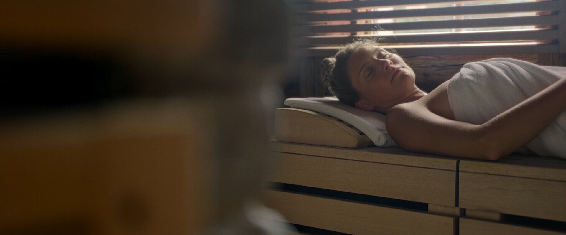 A person relaxing in a sauna wrapped in a towel, enjoying a peaceful moment.