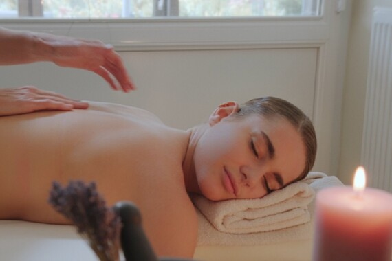 Eine Person genießt eine entspannende Massage in einem Wellnessbereich mit Kerzenlicht.