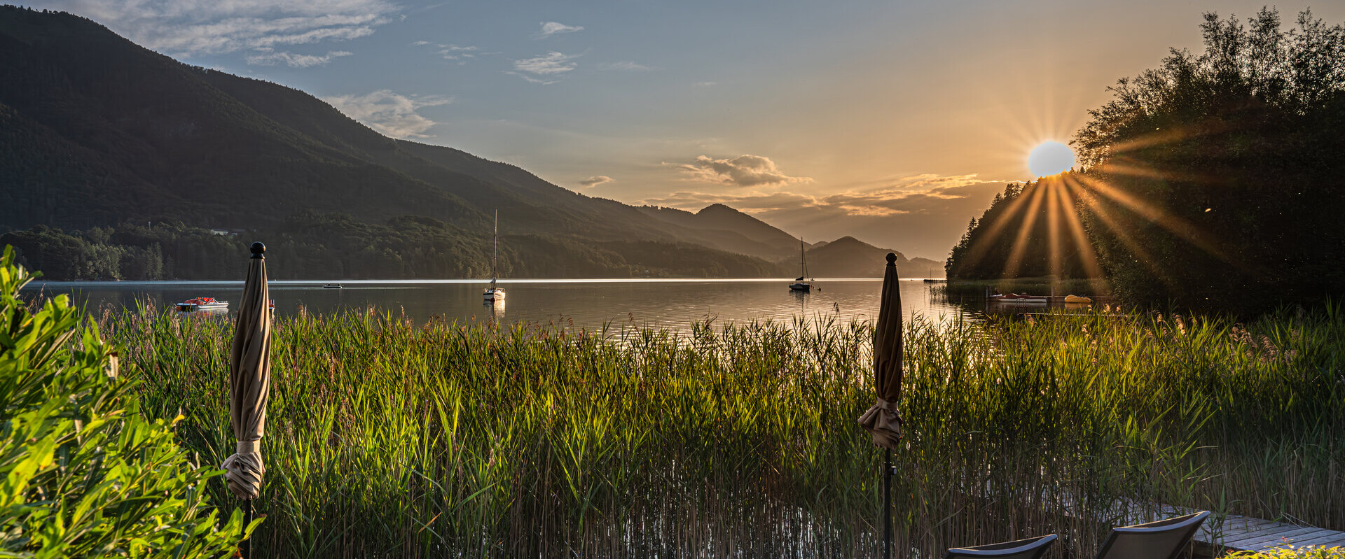 Sonnenuntergang am privaten Badestrand vom Waldhof Fuschlsee Resort, goldene Stimmung, ruhiger See mit Sträuchern