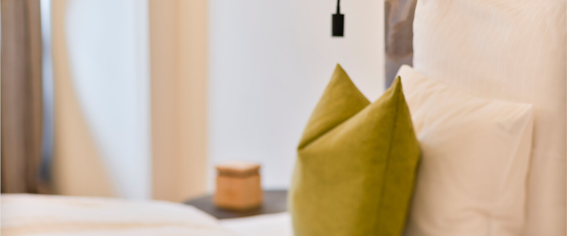 Hotelzimmer mit Wandlampe, bequemen Kissen und neutralen Farben im Waldhof Fuschlsee Resort.