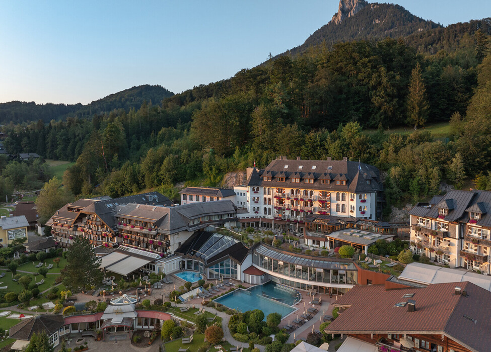 Aerial view of a scenic hotel surrounded by lush greenery and mountains.