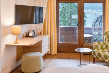 Cozy hotel room with a view of the lake, featuring a TV, lamp, and seating area.
