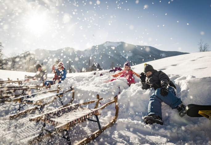 Kinder mit Schlitten im Tiefschnee auf der Waldhofalm am Fuschlsee.