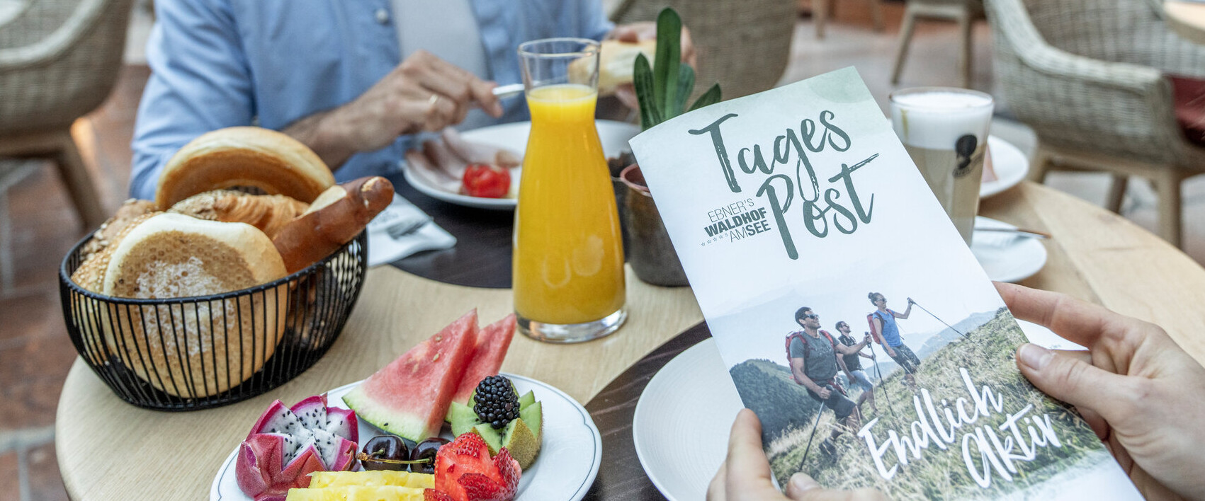 People enjoying breakfast in a cozy restaurant, with a focus on a brochure titled "Tages Post" on the table.