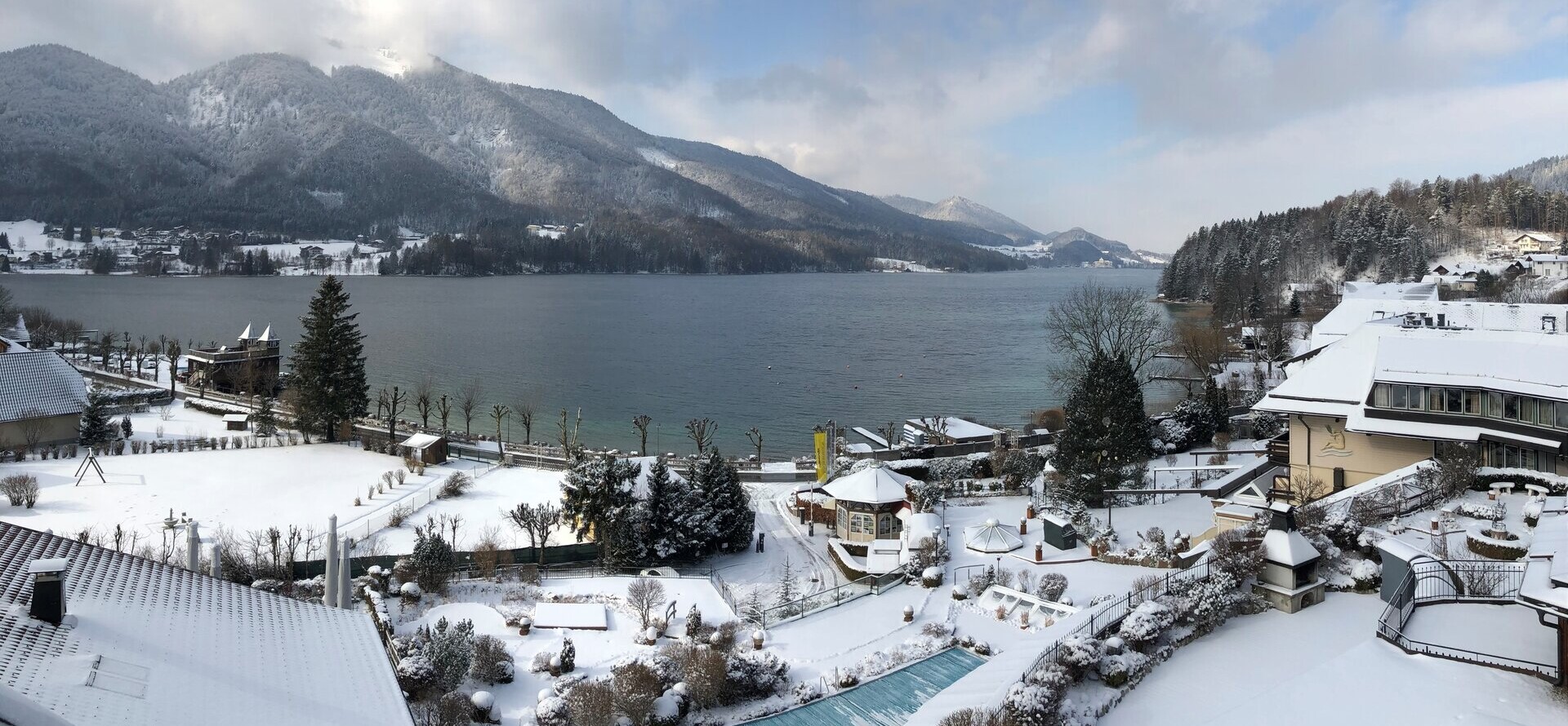Das 4* Superior Waldhof Fuschlsee Resort mit Schnee und Außenpool.