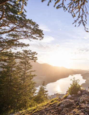 Pärchen vor einem Gipfelkreuz mit Blick auf en Fuschlsee.
