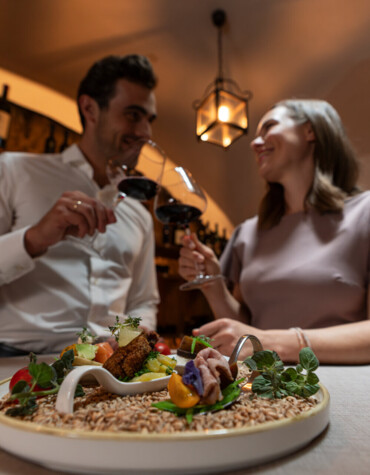 Pärchen beim Anstoßen mit einem Glas Wein im Waldhof Fuschlsee Resort.