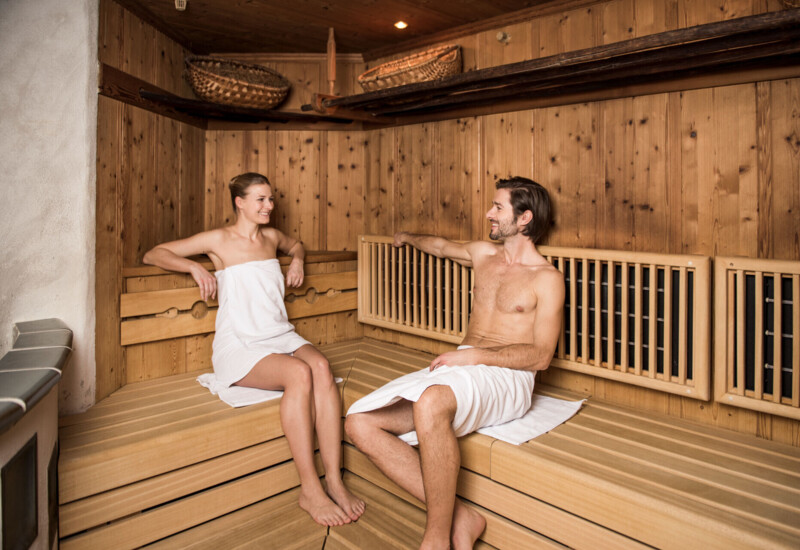 Ein Mann und eine Frau entspannen in einer Holzsauna.